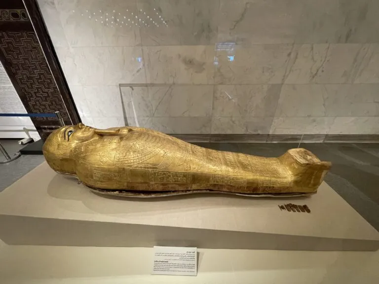 a gold statue of a person lying on a white surface