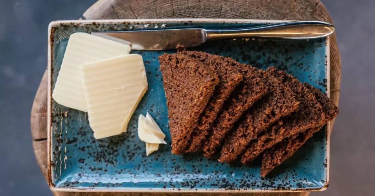 slices of rye bread cooked in geothermal heat paired with some butter, served on a plate to enjoy.