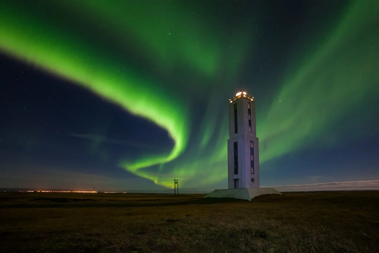 Knarraosviti white Lighthouse with green lights in the sky.