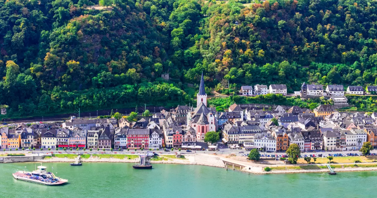 a city next to River Rhine in Germany with romantic cruise ship in it.