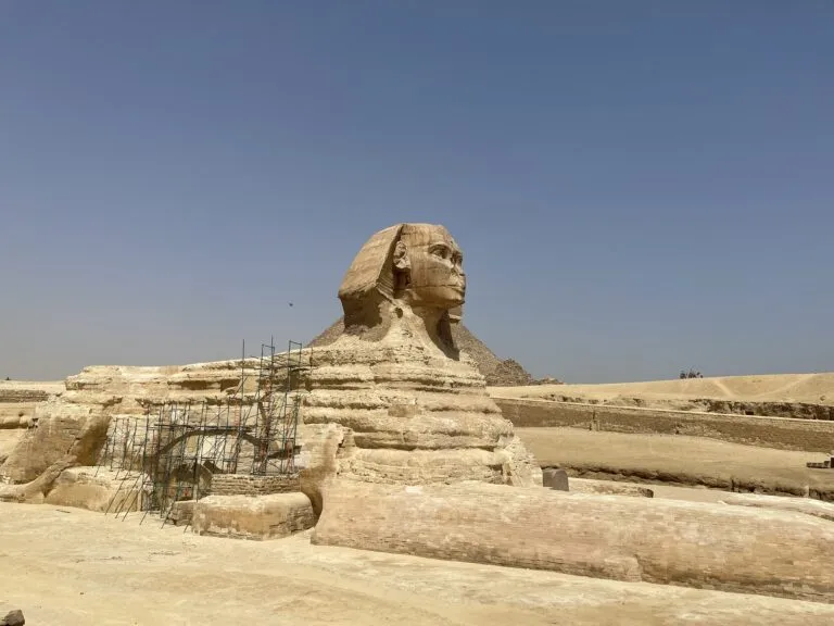 a stone statue of a man's face with Great Sphinx of Giza in the background