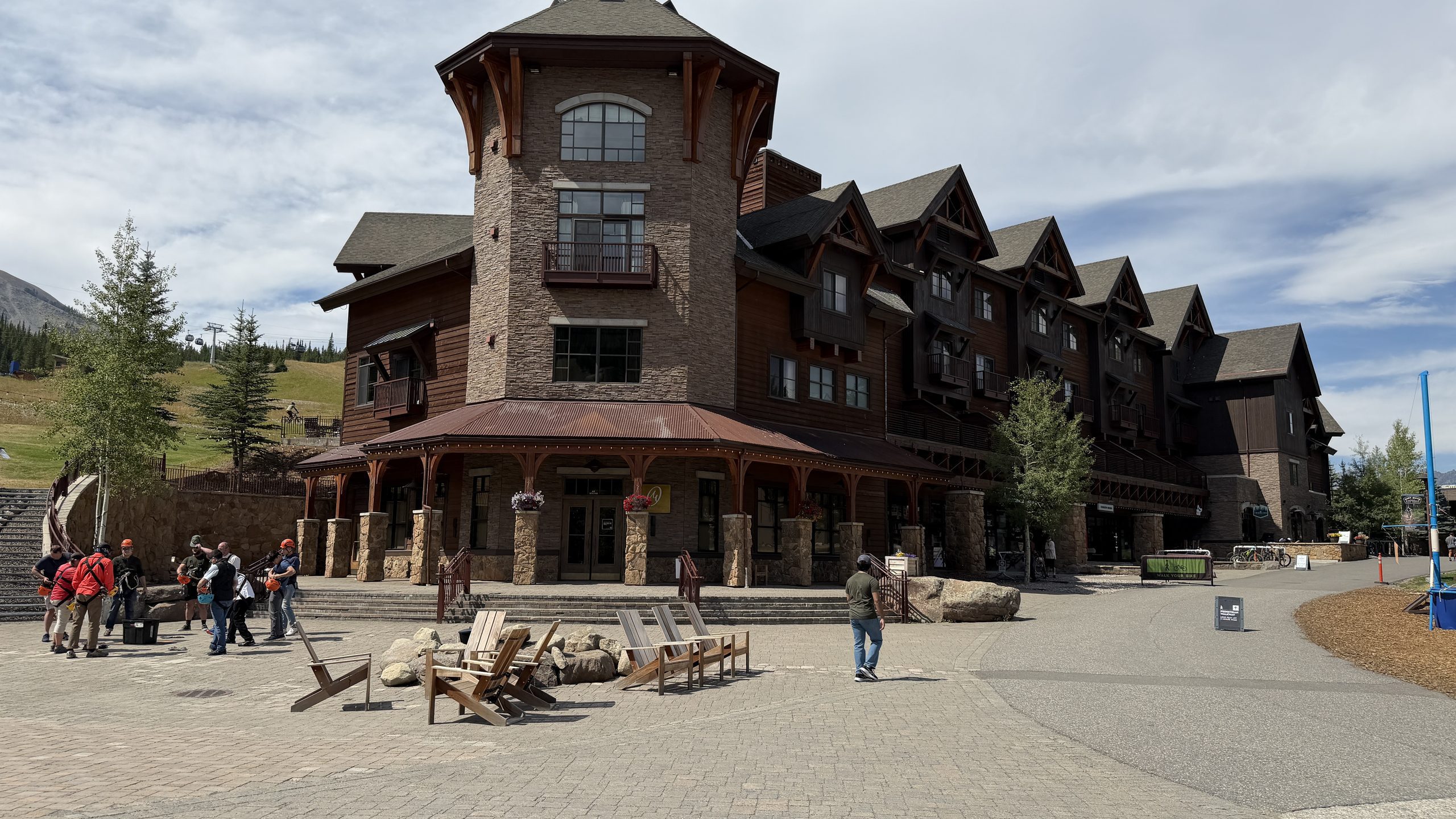 Stone and timber ski resort lodge building at Big Sky Resort with a paved plaza and outdoor seating.
