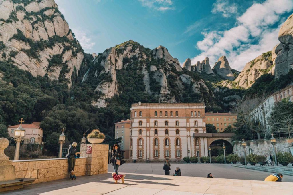 Santa Maria de Montserrat Abbey complex nested against the dramatic jagged rock peaks of Montserrat mountain in Spain